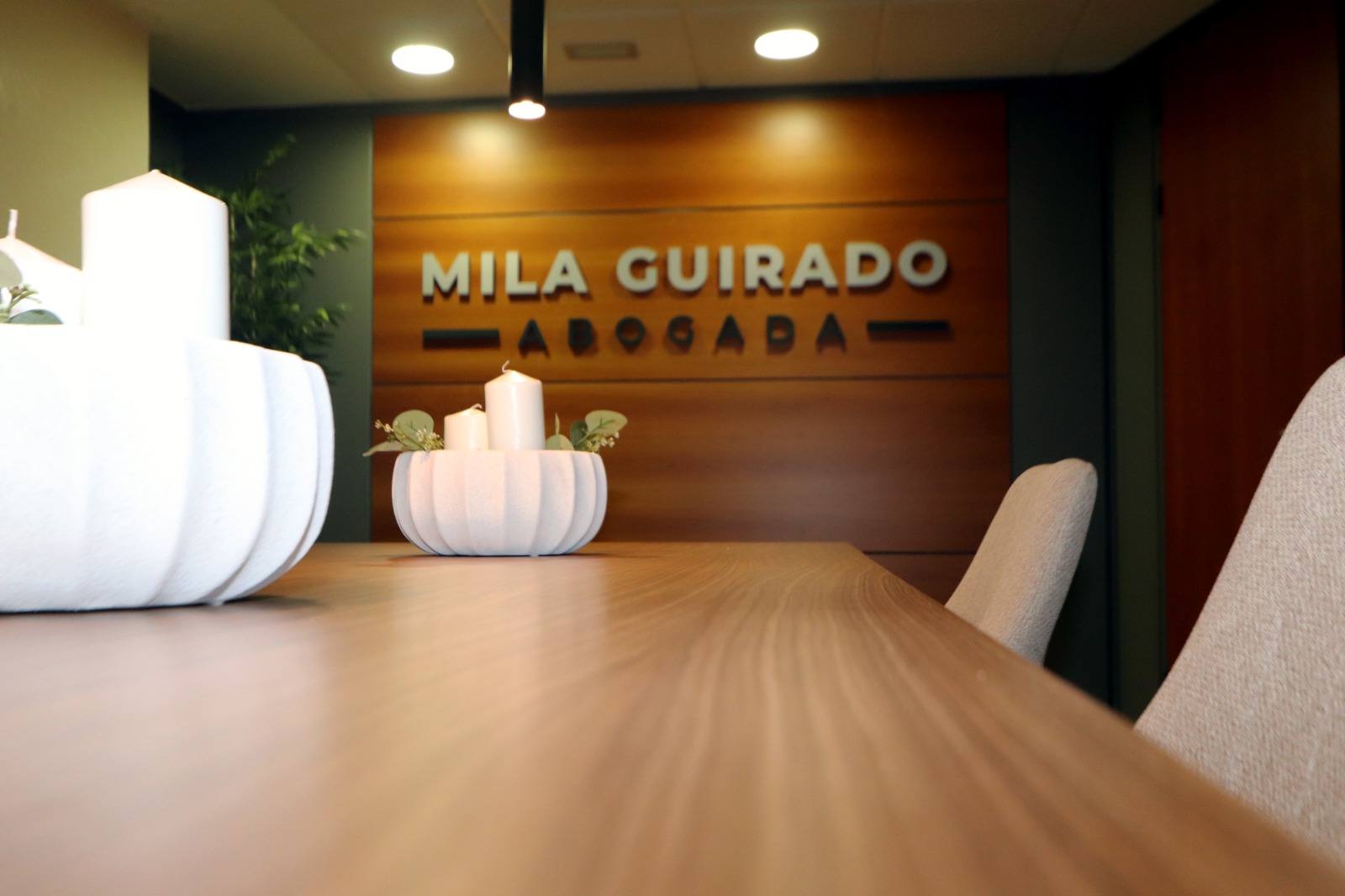 Mesa de reuniones de madera con el rótulo del despacho al fondo